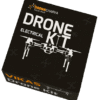 A black box for a "Drone Electrical Kit" made by Dronacharya Tech-Hub and Vikas. The box features a white line-art style illustration of a drone on the top face, along with the text "DRONE KIT" and "ELECTRICAL". The side of the box reads "VIKAS Drone Kit". Some small symbols that resemble an 'x' are also present on the box.