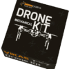 A product shot presents a black box labelled "Drone Mechanical Kit" with an orange logo at the upper left. The words "DRONE" and "KIT" are prominently displayed, separated by an illustration of a drone. Additional text in white reads "Mechanical" below "DRONE" and "VIKAS DRONE KIT" along the left side of the rectangular box. The box is slightly tilted and set against a white background.